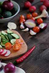Fresh vegetables sliced for a salad on a cutting board, on an old wooden table