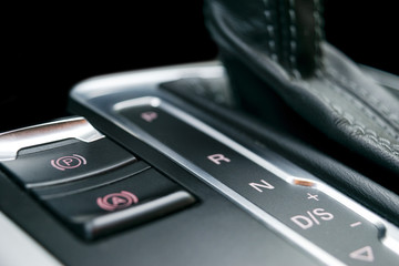 Automatic gear stick of a modern car. Maodern car interior details. Close up view. Car detailing. Automatic transmission lever shift. Black leather interior with stitching.