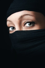 Naklejka premium Woman face close up with only eyes visible, rest of the face is covered with black scarf