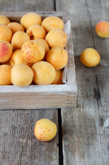Ripe apricots in a wooden box on a wooden table 