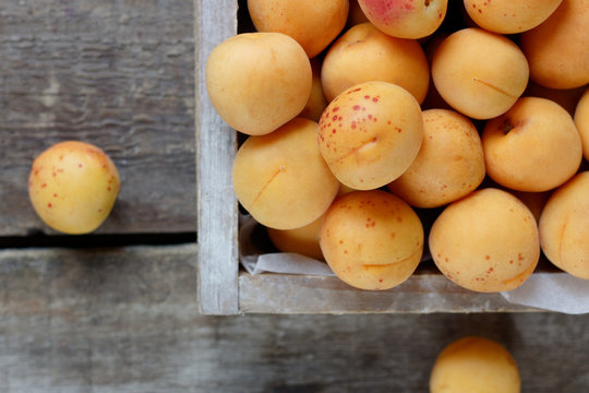 Ripe apricots in a wooden box on a wooden table 