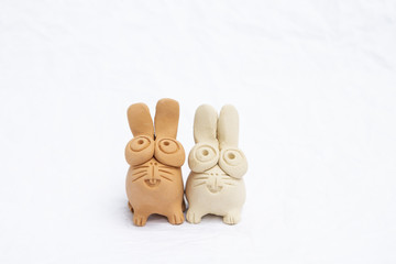 Two cute little clay rabbit doll for garden decoration on white background, handmade clay rabbit, Easter bunny decorate