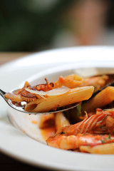 Penne pasta tomato sauce arabiata with seafood on wood background vintage style