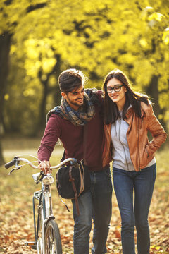 Young couple riding bicycle outdoors at autumn at the park.