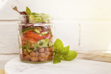 Healthy Vegetable Salad in Mason Glass Jar with Tomato, Beans, Lettuce, Broccoli. Take Away Food. Rustic Style. Lunch for work.