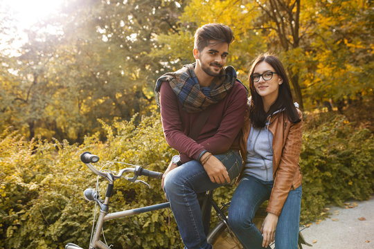 Young couple sitting on bicycle at the park on autumn day.Love  couple concept.