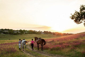 Two woman and two horses outdoor in summer happy sunset together nature