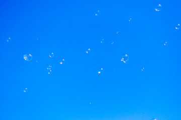 Soap bubbles in flight against the blue sky