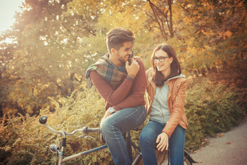 Young couple sitting on bicycle at the park on autumn day.Love  couple concept.