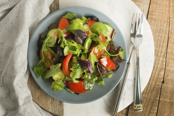 Fresh Green Salad with Mix Greens Leaves Spinach, Augula, Basil, Lettuce, tomatoe, Cucumber. rustic Style, Wooden Background. Health and Dietting.