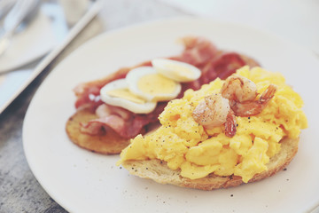 breakfast with scrambled eggs, fried potatoes bacon and shrimp