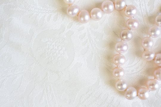 White silk satin background close up with pearl necklace - Top view photo