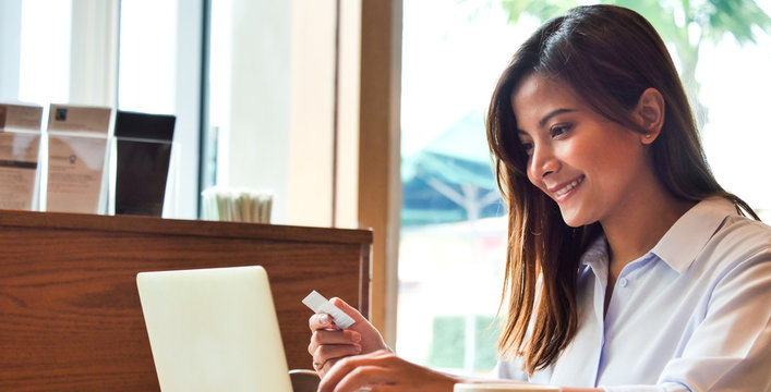 Branner Close up asain woman hands with creadit card and laptop in coffee shop.