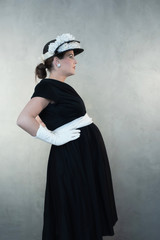 Retro 1950s pregnant woman in black dress and hat.