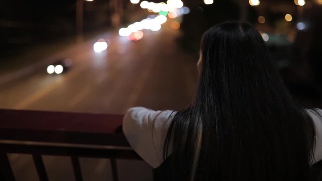 Young woman listening to music standing on a bridge at night time