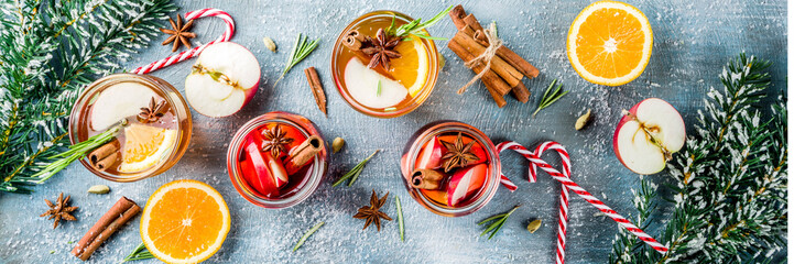 Traditional winter drinks, white and red mulled wine cocktail,  with white and red wine, spices, apple, orange. On a light blue table, banner