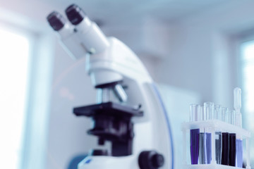 In the lab. Selective focus of test tubes with different liquids with modern professional microscope standing in the background