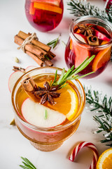 Traditional winter drinks, white and red mulled wine cocktail,  with white and red wine, spices, apple, orange. On white marble background copy space