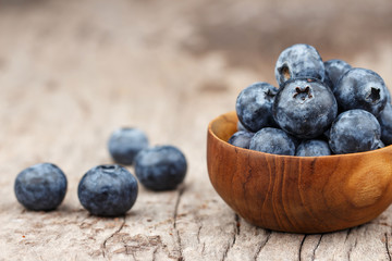 Blueberries in a wood bowl on a wooden table, Healthy eating and nutrition concept
