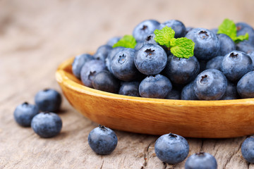 Blueberries in a wood bowl on a wooden table, Healthy eating and nutrition concept