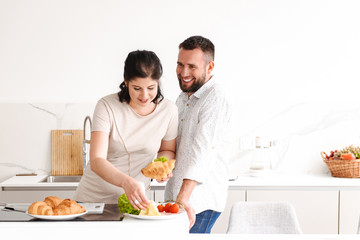 Portrait of beautiful family happy man and woman cooking, and having breakfast in bright kitchen