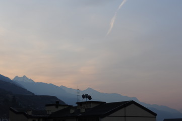 Roofs of Saint-Vincent town in Aosta valley (Valle d’Aosta) in Italy with Italian Alps in winter at dusk