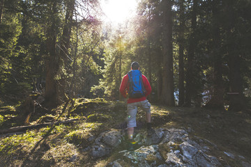 hiking man with blue backpack and red sweater in the forest