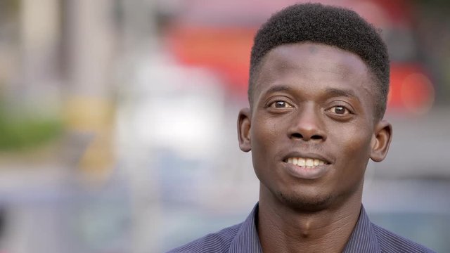 black american youn man in the street raising his head and smiles at camera