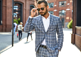 Portrait of sexy handsome fashion businessman model dressed in elegant checkered suit posing on...
