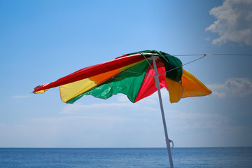 Beach umbrella broken by the wind. Beginning storm.