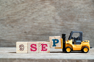 Toy forklift hold block P to complete word 9 sep on wood background (Concept for calendar date in month September)