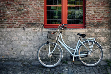 Fototapeta na wymiar Bicycle with basket in fromt of old wall with red window