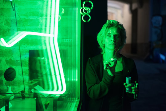 Night Portrait Of Young Woman With Soap Bubble Near Green Neon Showcase. Art Concept