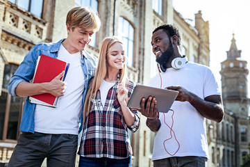 It is my plan. Handsome blonde man expressing positivity while standing near his girlfriend and holding project works