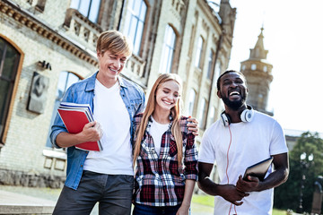 Time to relax. Positive delighted students standing together and looking downwards while smiling
