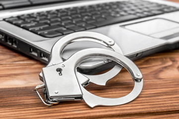 op with handcuffs on the table. Cybercrime concept.