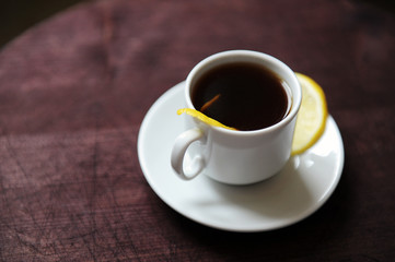 Espresso romano coffee with lemon in a white cup on a dark wooden table close up