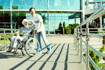 Fototapeta premium Cannot see. Joyful female person raising her left hand and looking sideways while being on the wheelchair