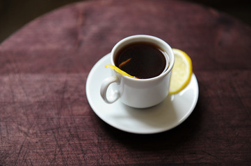 Espresso romano coffee with lemon in a white cup on a dark wooden table close up