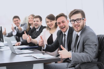 business team with thumbs up while sitting at his Desk