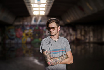 Serious young adult tattooed man under the bridge , subculture concept 