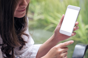 Mockup image of a woman holding and showing white mobile phone with blank screen in cafeMockup image of a woman holding and showing white mobile phone with blank screen in cafe