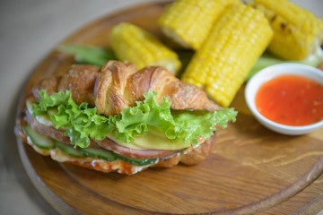 Wonderful croissant with ham and corn grilled on a chopping board
