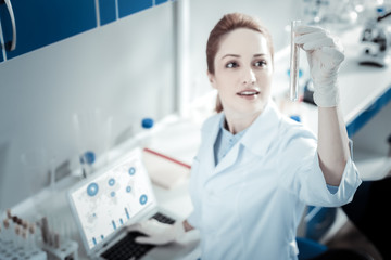 Modern lab. Selective focus of a test tube being in hand of nice smart female scientist while working in the lab