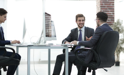 Image of two young businessmen interacting at meeting in office