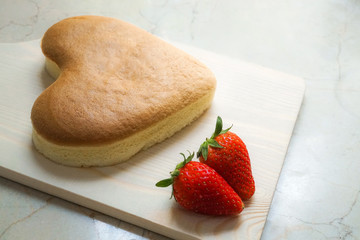 heart shape cheese cake with strawberry on wooden chopping board for valentine's day