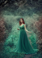 Red-haired girl in a green, emerald, luxurious dress in the floor, with a long train. The princess walks in a fairy forest. Simple and elegant hair in large waves. Artistic retouching © kharchenkoirina
