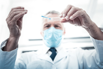 Medical lab. Selective focus of glass with a drip of test sample on it being held by smart...