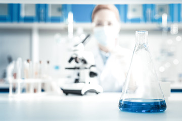 Organic chemistry. Selective focus of a flask being filled with chemical reagent standing on the...