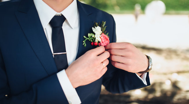 The groom puts on his wedding boutonniere. Wedding preparations. Adjust flowers.